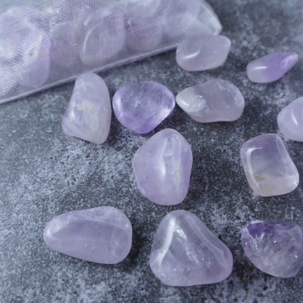 Dumi's Crystals | Light Amethyst Chips (1-1.5cm) | Close-up of a collection of genuine Light Amethyst chips, highlighting their soft lavender color and variations in texture. Light Amethyst is revered for its ability to promote inner peace, focus, and creative inspiration.