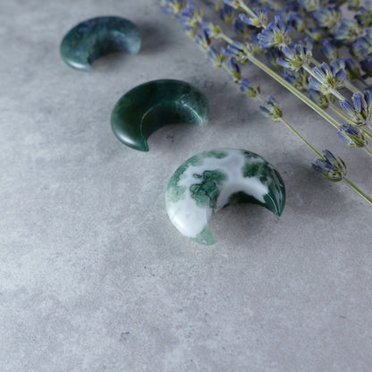 Find Peace in Nature - Dumi's Crystals Moss Agate Moon (3cm). Hand-carved moonstone with green inclusions fosters emotional balance and a connection to the Earth.