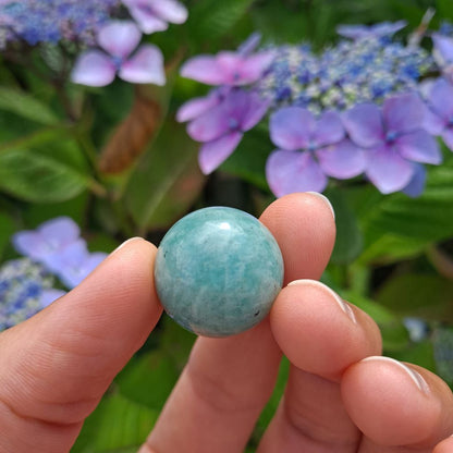  Dumi's Crystals | Amazonite Mini Sphere (20mm) | A close-up view of a captivating Amazonite Mini Sphere, showcasing its smooth, polished surface and mesmerizing blend of green and blue hues. This 20mm sphere radiates calming energy, promoting peace, communication, and emotional balance.