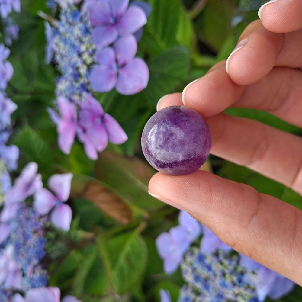 Dumi's Crystals | Chevron Amethyst Mini Spheres (20mm) | A collection of captivating Chevron Amethyst Mini Spheres, each displaying unique variations of purple and white chevrons. These 20mm spheres are believed to promote balance, clarity, spiritual growth, and protection. Perfect for meditation, crystal grids, or carrying with you throughout the day.