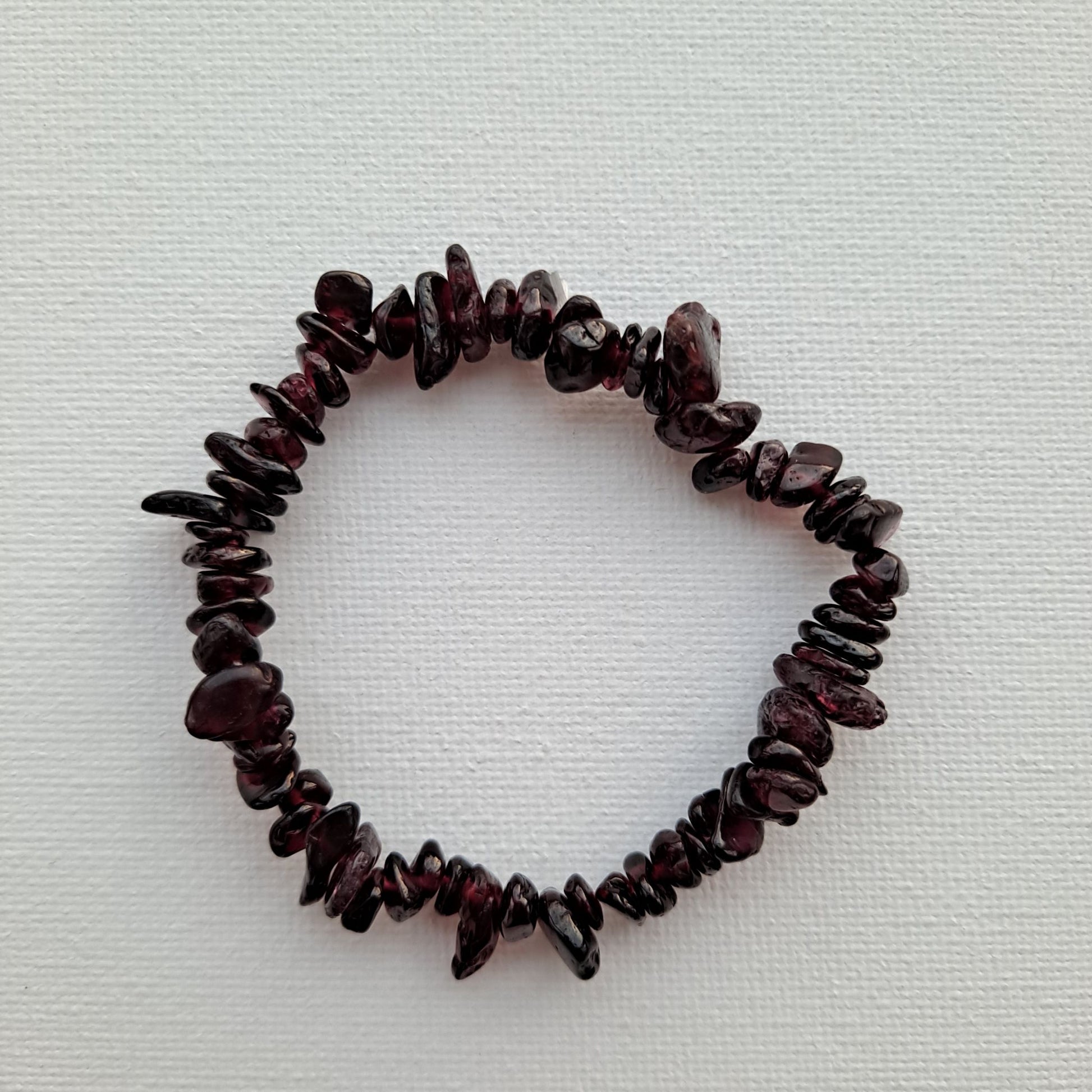 Dumi's Crystals | Garnet Stretch Bracelet (7 Inch) | Close-up of a handcrafted bracelet featuring genuine Garnet beads. The rich red color exudes warmth and energy. Garnet, a birthstone for January, is believed to promote passion, strength, and vitality.