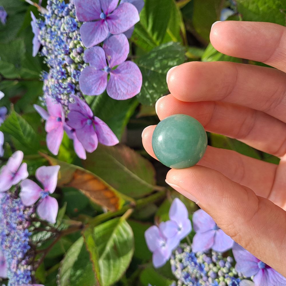 Dumi's Crystals | Green Aventurine Mini Sphere (20mm) | A close-up view of a captivating Green Aventurine Mini Sphere, showcasing its vibrant green hues and glistening sheen. This 20mm sphere is believed to promote peace, love, abundance, and emotional healing. It's also thought to attract good fortune and encourage optimism.