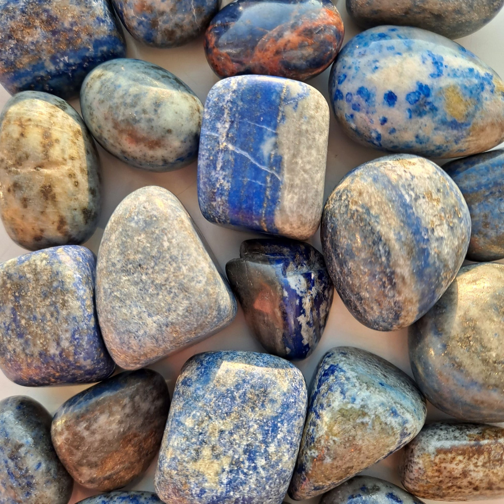 Dumi's Crystals | Lapis Lazuli Tumbled Stones (Clarity & Enlightenment) | A collection of Lapis Lazuli Tumbled Stones, each a reminder of the celestial realm. Lapis Lazuli fosters self-awareness, reduces stress & awakens intuition. Scatter them in your home or workspace to create a space overflowing with wisdom and a connection to your higher self.