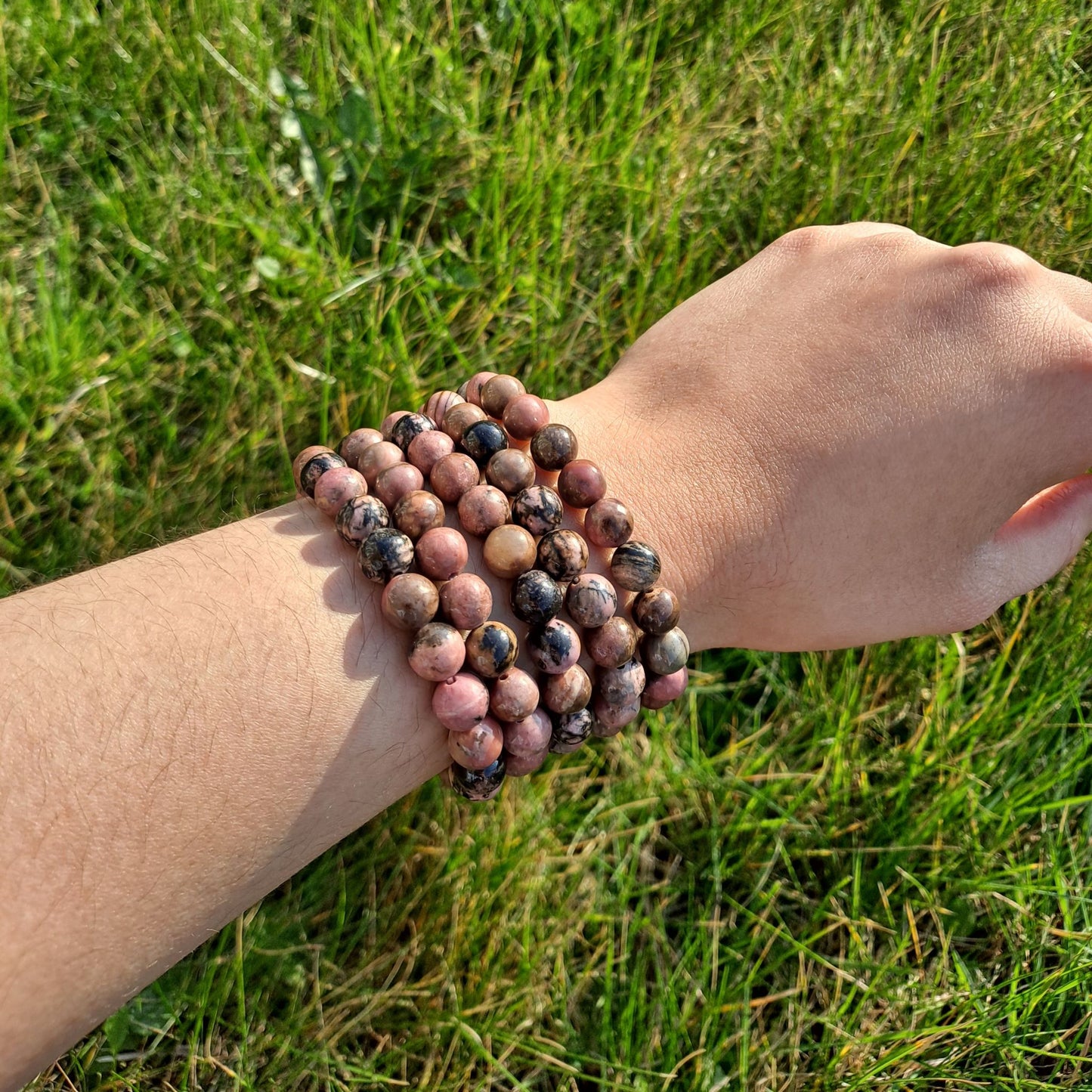 Dumi's Crystals | 8mm Rhodonite Stretch Bracelet (7 Inch) | Close-up of a handcrafted bracelet featuring genuine 8mm Rhodonite beads in rich pink hues with contrasting dark veins. Rhodonite is known as the stone of compassion and is believed to promote emotional healing and self-love.