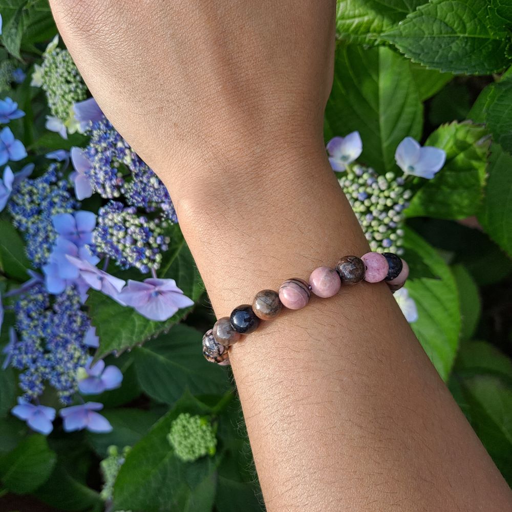 Bold 8mm Rhodonite bracelet for love and compassion on wrist | Dumi's Crystals | Embrace strength & inner peace with this Rhodonite stretch bracelet. Rich pink tones, promotes emotional balance and strong relationships.