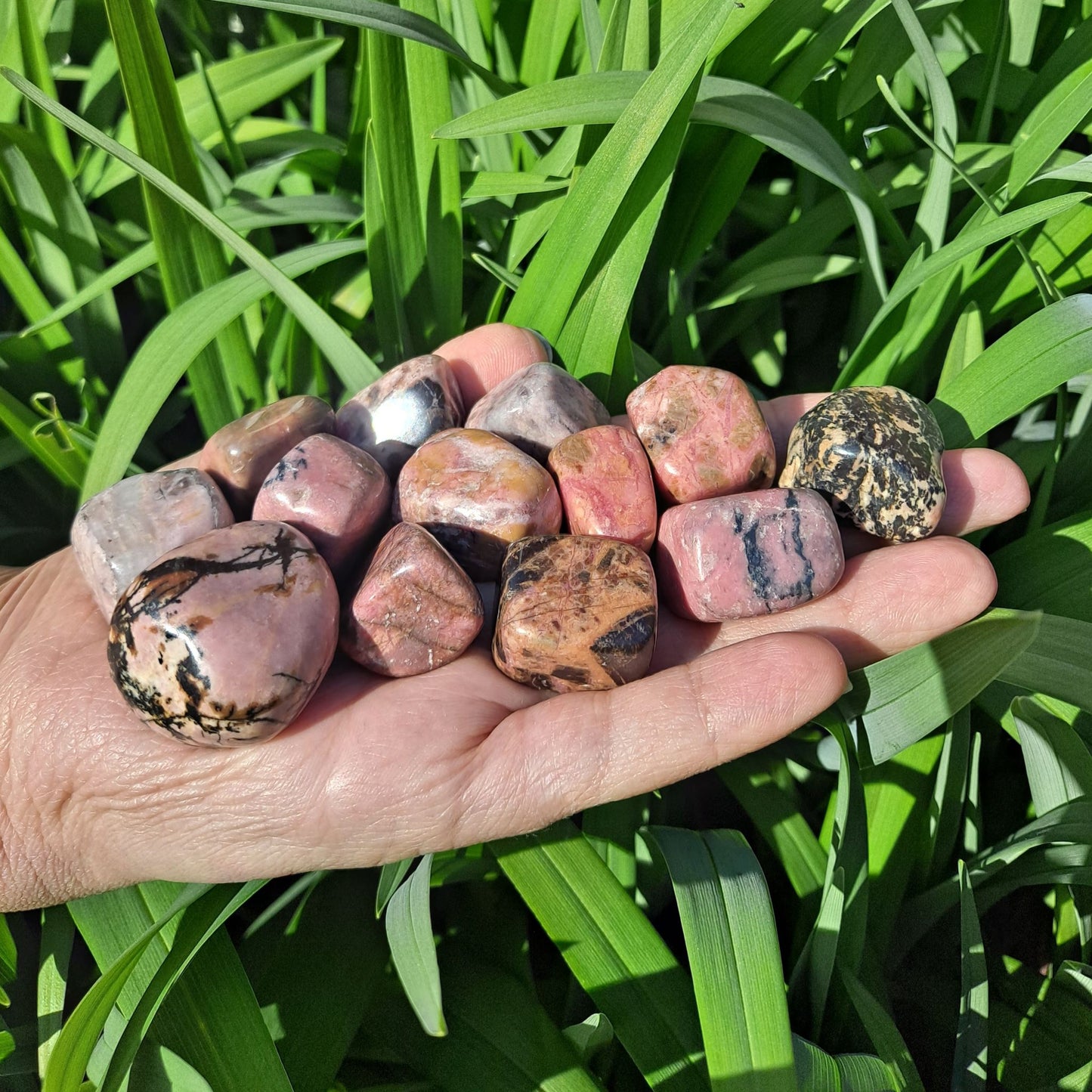 Dumi's Crystals | Rhodonite Tumbled Stones (Love & Compassion) | A handful of Rhodonite Tumbled Stones radiate a calming pink hue. Known for promoting love, emotional healing & forgiveness, hold them during meditation or carry them throughout the day to cultivate a heart filled with compassion and peace.