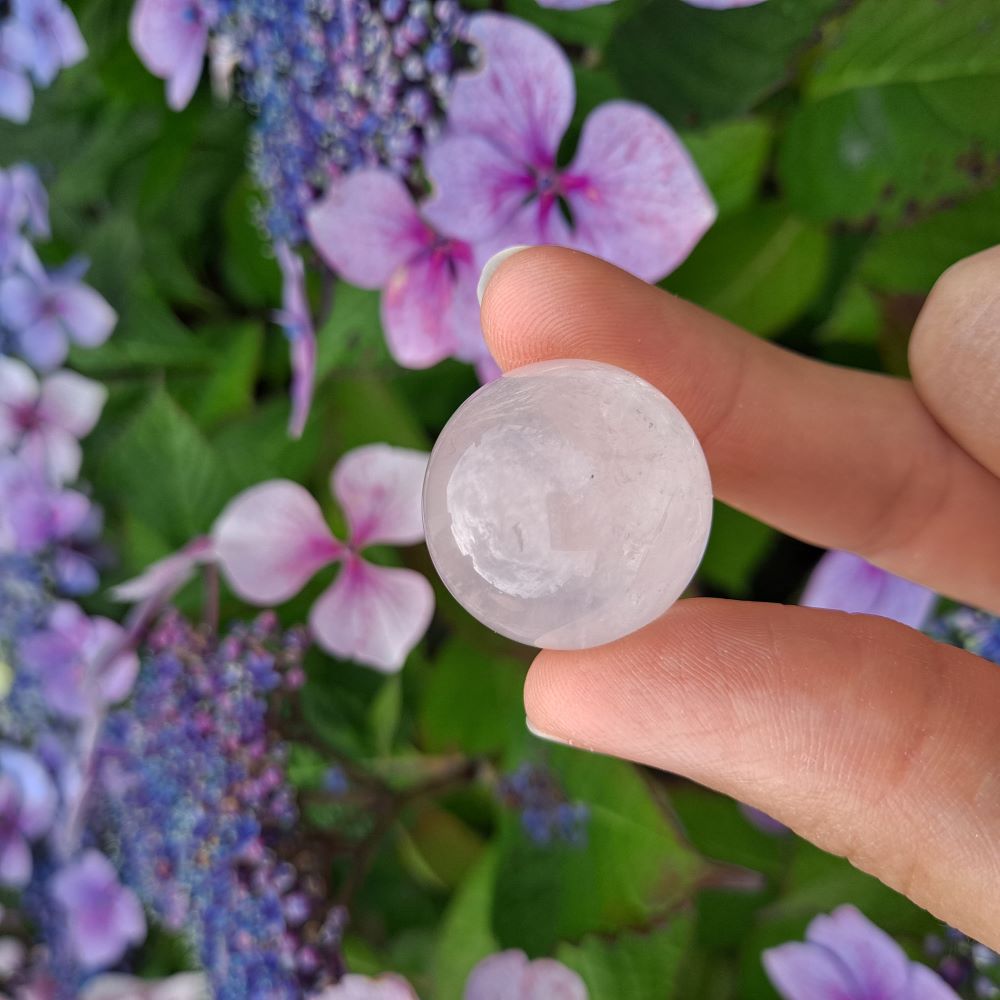 Dumi's Crystals | Rose Quartz Sphere (25mm) | A close-up view of a captivating Rose Quartz Sphere (25mm), showcasing its delicate pink hue and soft luster. This gemstone, known as the Stone of Unconditional Love, radiates pure heart-opening energy. It's believed to promote love, compassion, emotional healing, and self-acceptance.